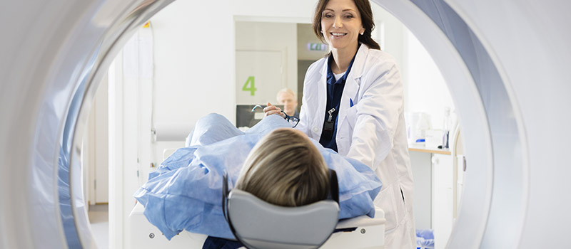 female radiology doctor leading patient into the radiology machine to be scanned
