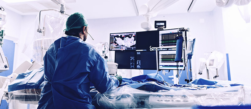 male radiology doctor working on a patient doing a scan while watching the computer monitors