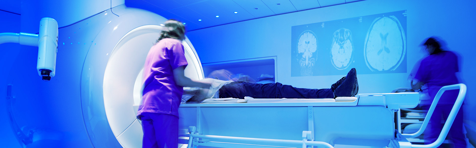 action shot of two radiology nurses prepping a patient to get scanned in the radiology machine